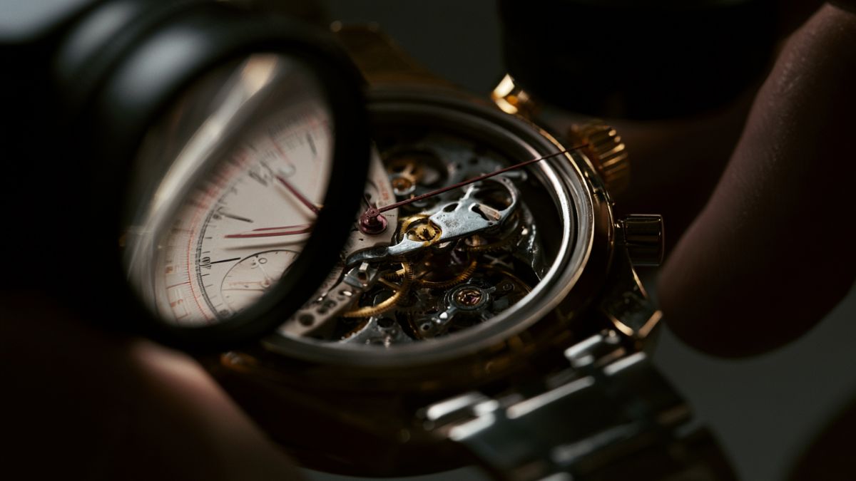 A loupe inspecting a watch dial and movement, illustrating the forensic framework for evaluating a mechanical watch before buying
